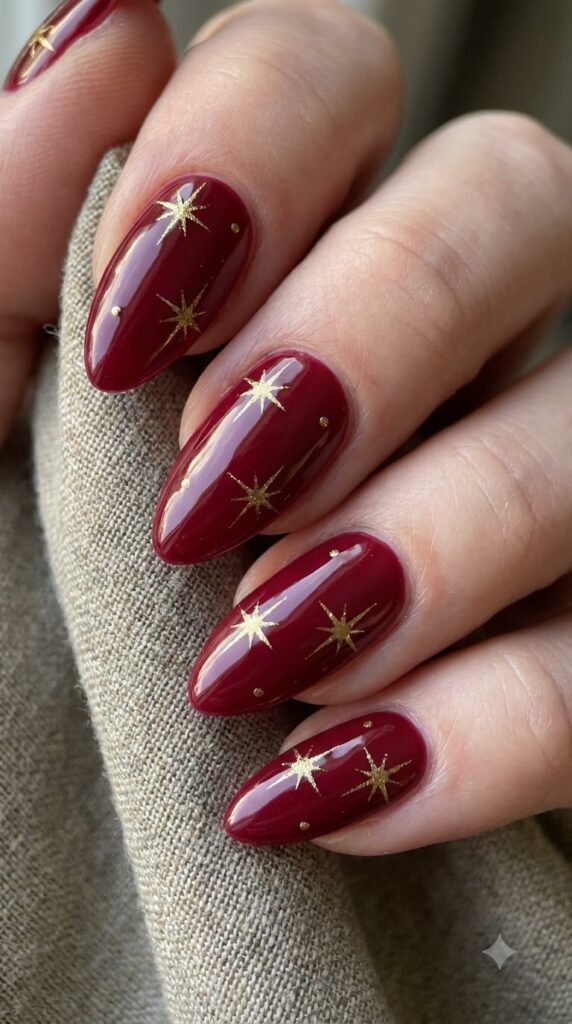 Almond glossy dark crimson red nails decorated with golden starbursts