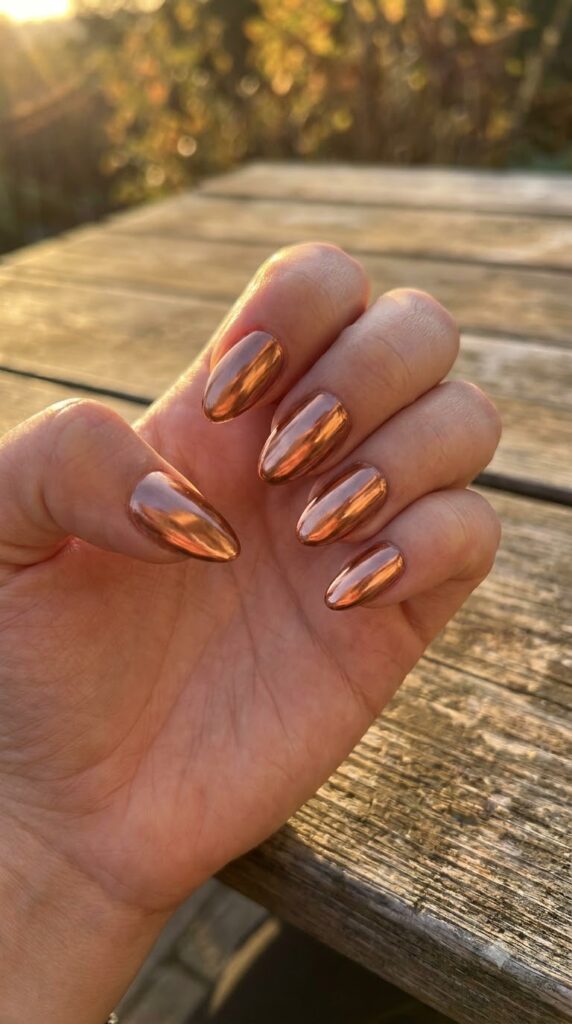 Medium almond nails painted in liquid metallic copper mirror chrome powder