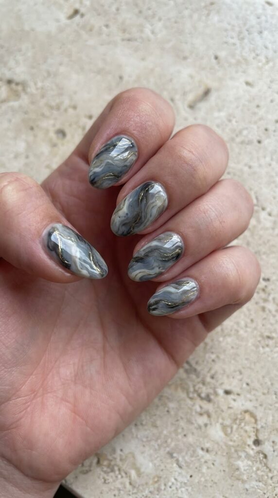 Short almond nails with swirled gray, white, charcoal, and gold marble art