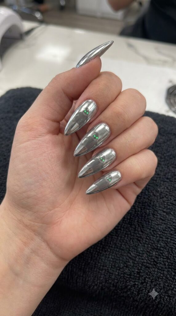 Stiletto silver metallic chrome nails with black Oogie shadow and green eyes