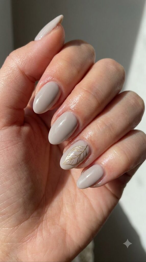 Short almond gray nude nails with a fine metallic gold leaf outline