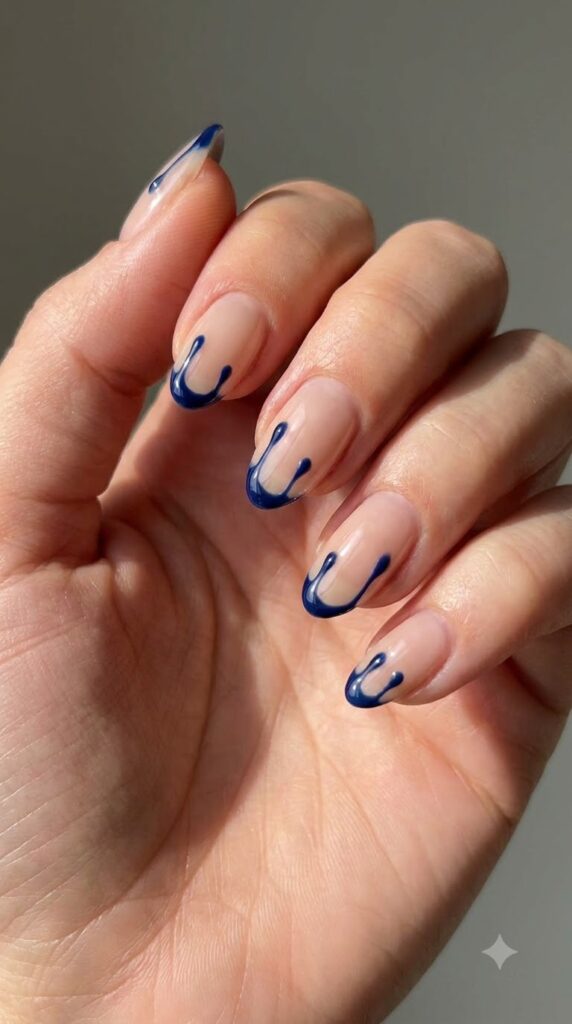 Short almond nude nails with ultra-thin glossy navy blue drip tips