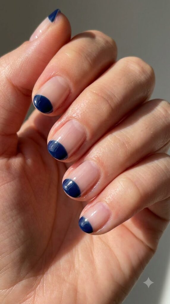 Short round clear nails with painted deep navy blue cuticle half-moons