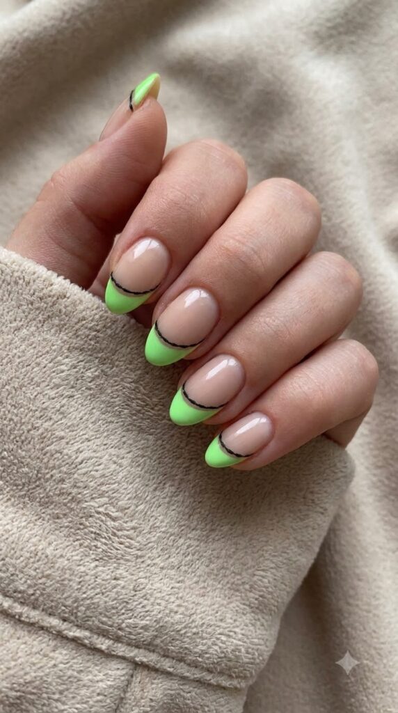 Short almond nude nails with neon green side tips and black burlap stitches