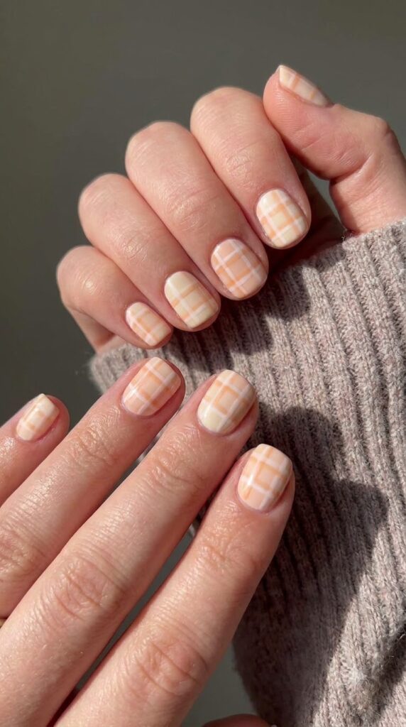 Short square peach nails decorated with a fine cream gingham grid