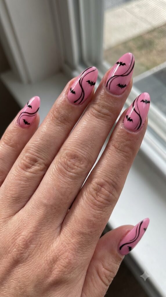 Long almond bubblegum pink nails with black swirls and flying bats