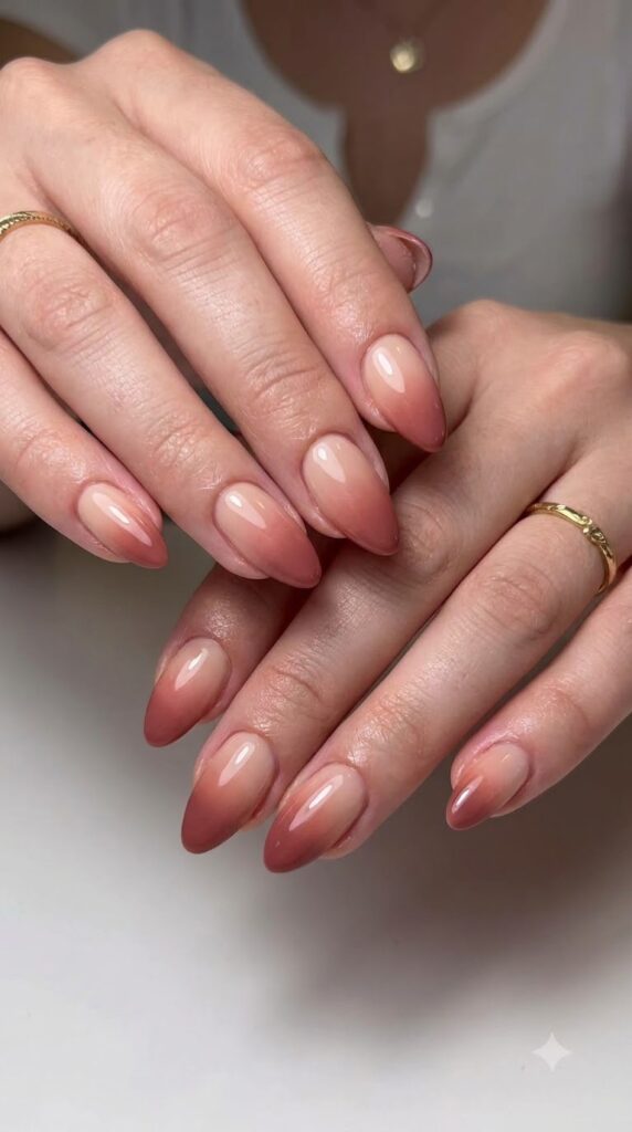Almond nails with nude base fading smoothly into deep cinnamon pink tips