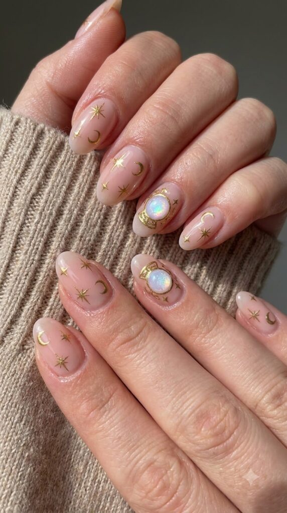 Oval blush pink nails with gold starbursts, moons, and crystal ball art