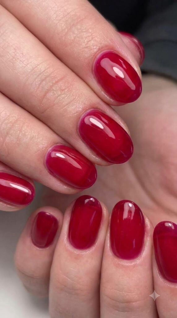 Short oval translucent ruby red jelly nails with glass-like candied shine