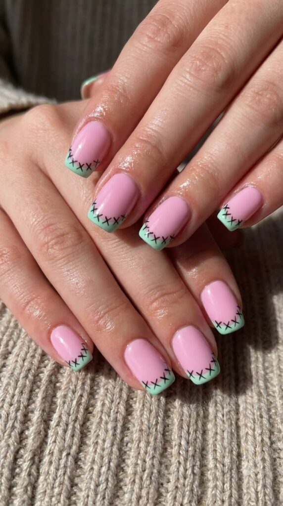 Short square pink nails with mint green French tips and Frankenstein stitches