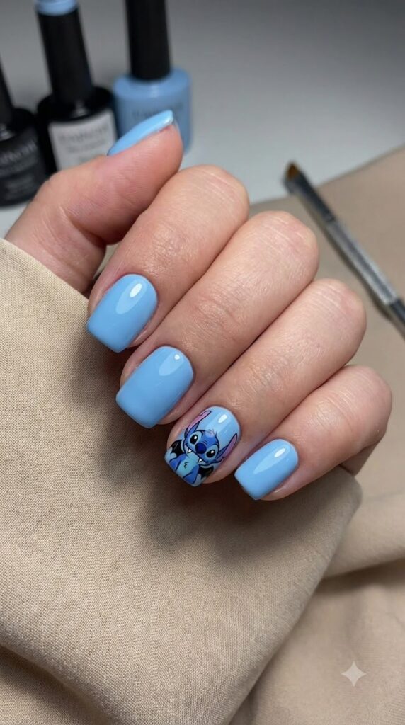 Short squoval blue nails with Stitch wearing black bat wings accent