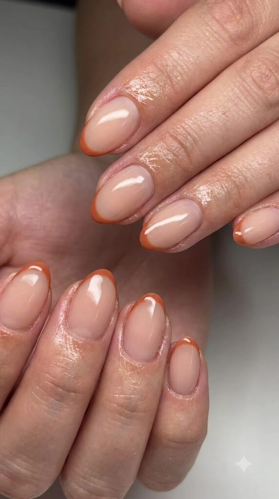 Short almond nude nails with ultra-thin terracotta orange French tips
