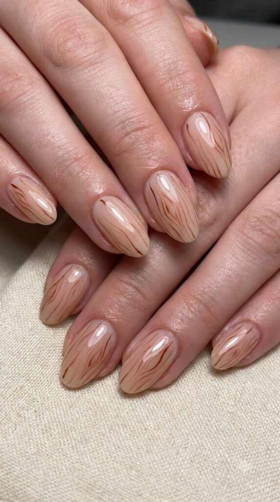Oval nude nails with subtle hand-painted mahogany wood grain line art