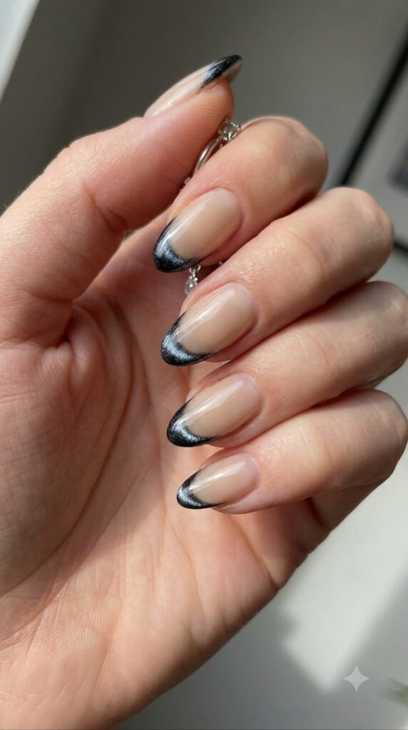 Short almond nude nails with micro French tips in black magnetic cat-eye polish