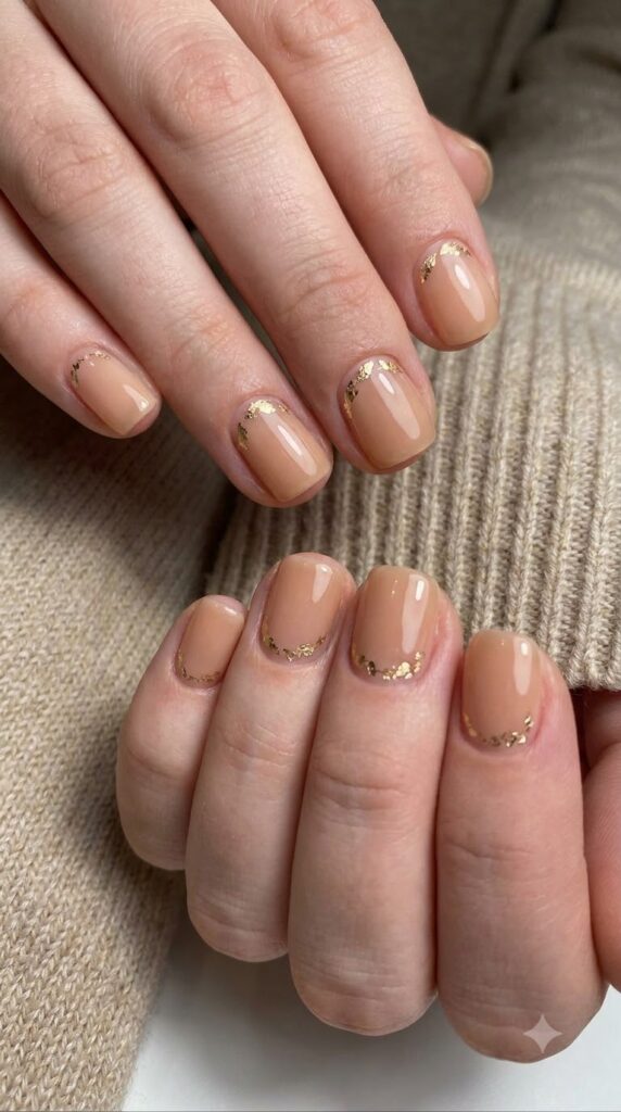 Short natural squoval nude nails decorated with champagne gold leaf foil flecks