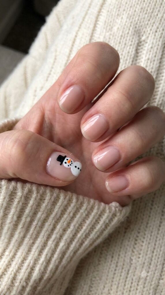 Short round blush nude nails with a miniature painted snowman wearing a top hat