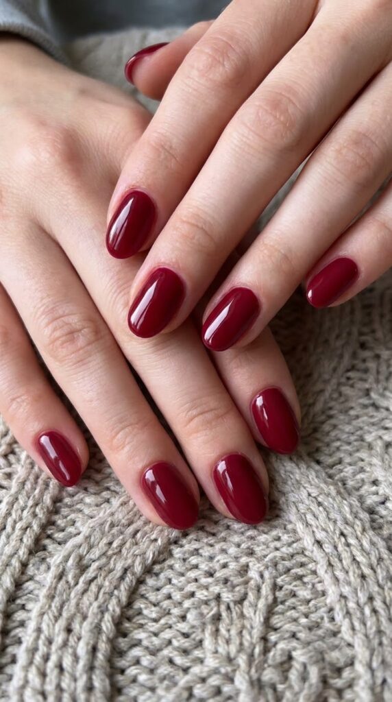 Medium almond nails painted in opaque deep cranberry wine red polish