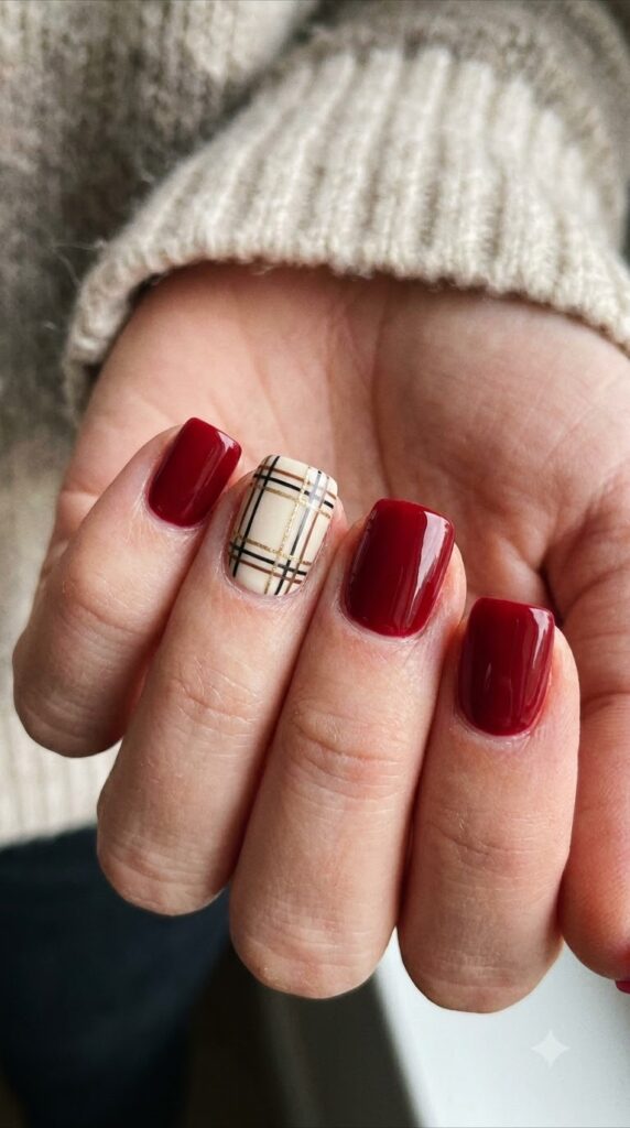 Short square red nails with a cream accent nail featuring black brown gold plaid art