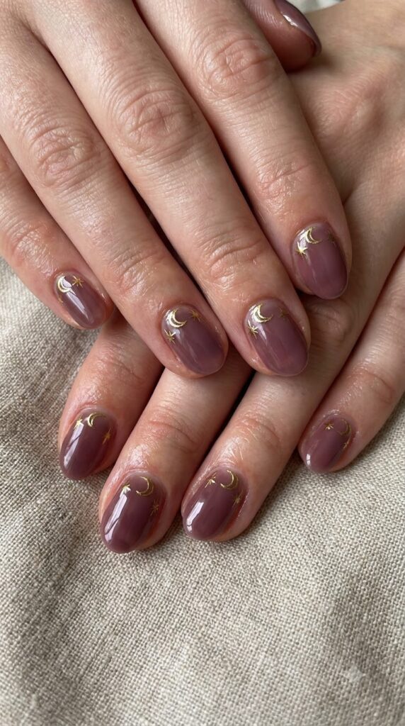Short oval deep plum nude nails decorated with metallic gold crescent moons
