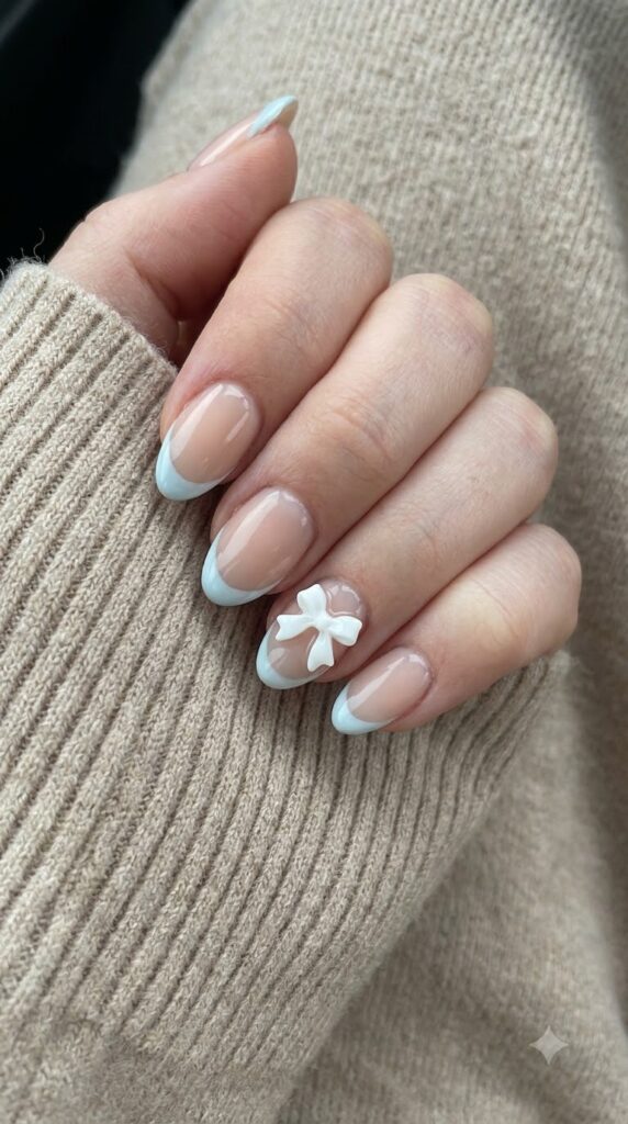 Short almond nude nails with pale icy blue French tips and 3D white gel bows