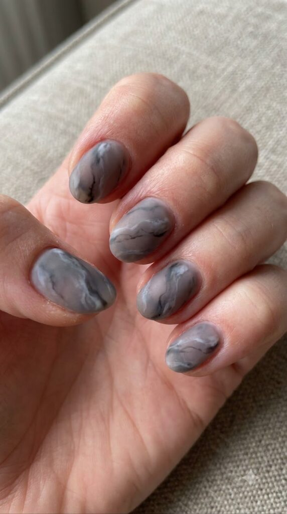 Short oval smoky grey marble nails swirled with white charcoal veins in matte