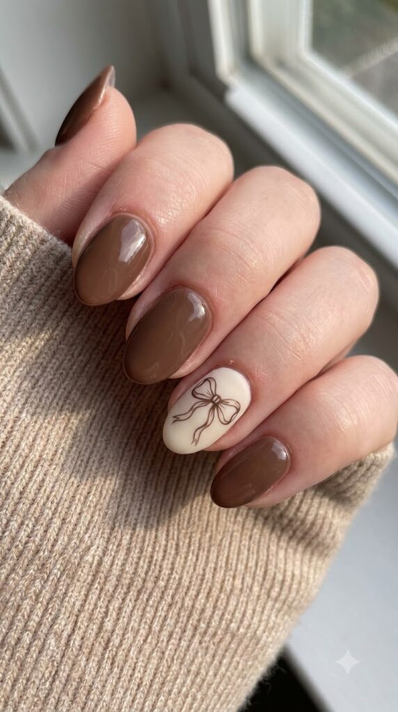 Short almond mocha brown nails with cream ribbon bow line art