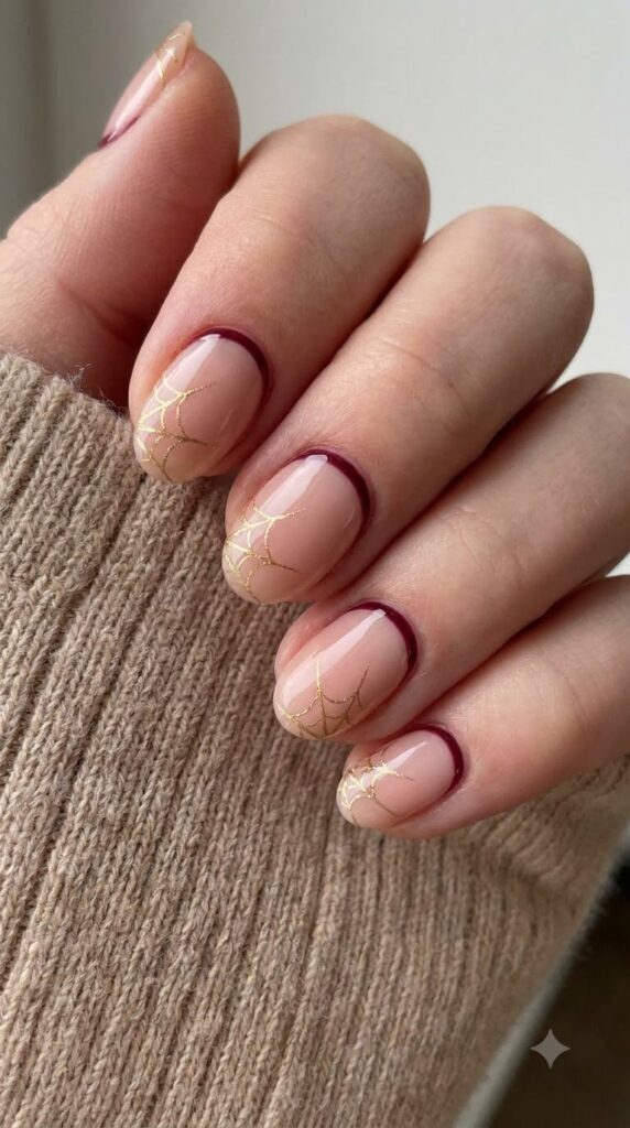 Short oval nude nails with deep maroon cuticle lines and gold web line art