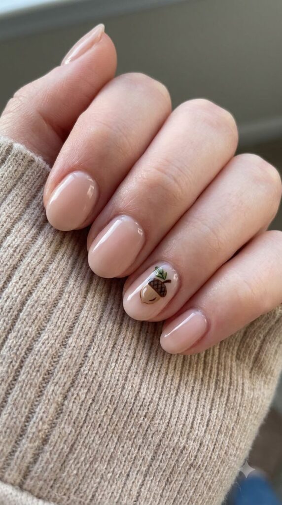 Short oval blush nude nails with a miniature hand-painted acorn accent