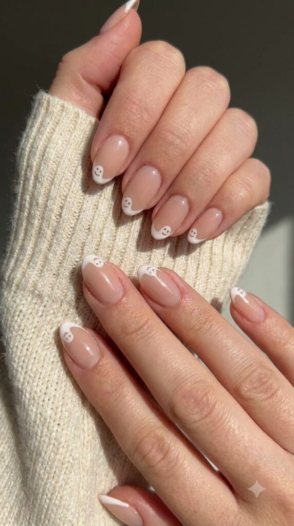 Short almond nude nails with ultra-thin white French tips forming tiny ghost faces