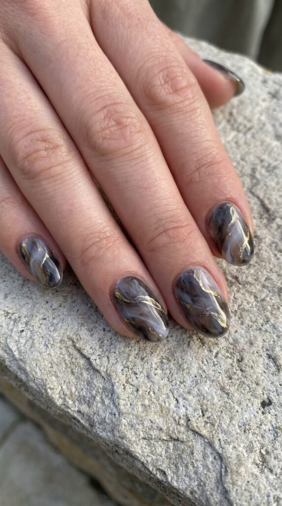 Short oval smoky grey marble nails swirled with soft white and gold veins