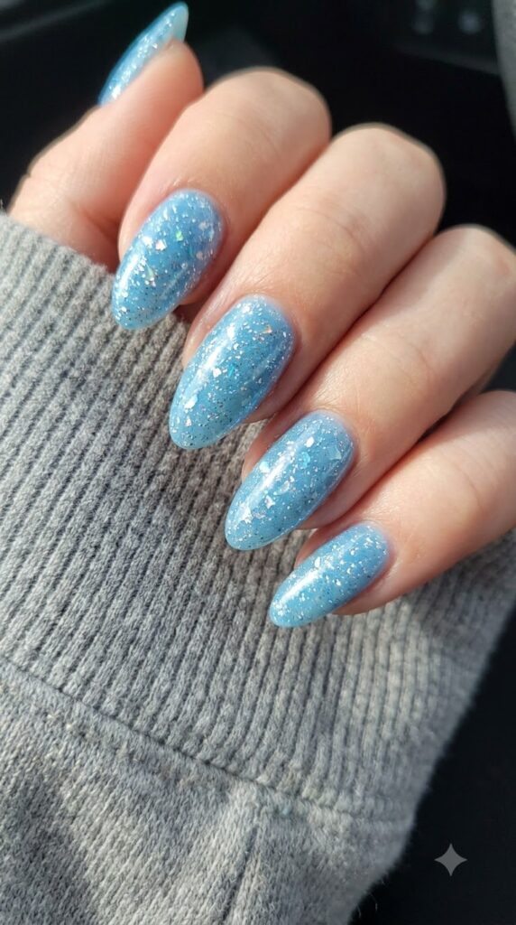 Medium almond sky blue nails filled with dense silver micro-glitter and ice flakes