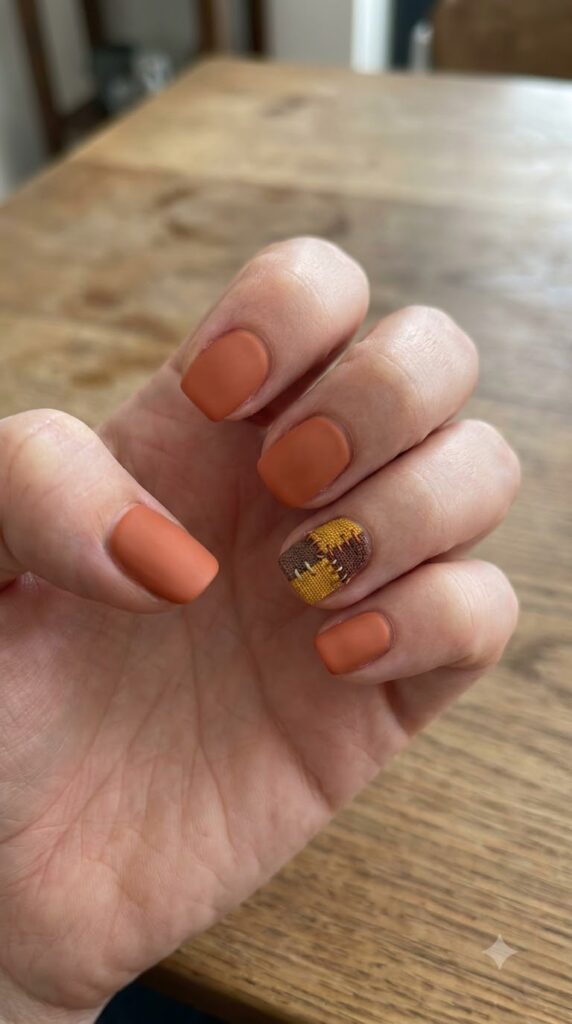 Short square terracotta orange nails with brown and mustard fabric patches