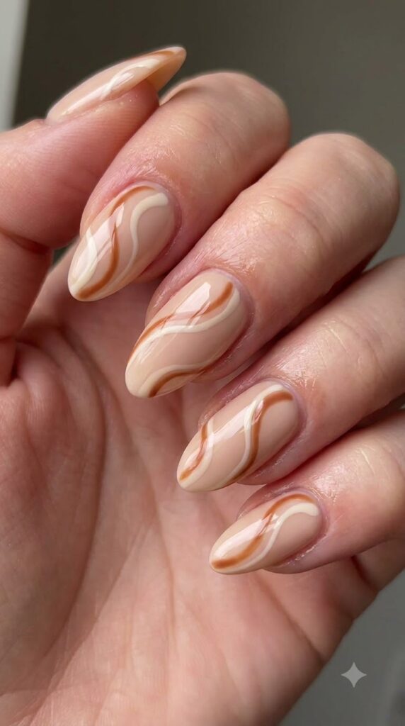 Almond nails with nude base and toasted cinnamon brown swirl lines